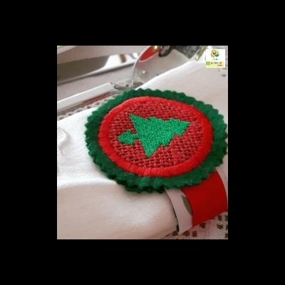 Emblema bordado de árvore de Natal verde sobre fundo vermelho com bordas verdes em peça de roupa branca.