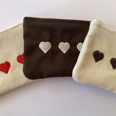 Três bolsas pequenas em tecido com corações bordados em fecho