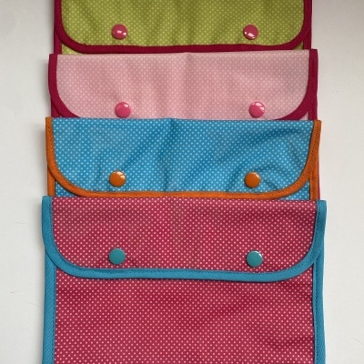 Quatro bolsas retangulares coloridas com padrões de bolinhas e botões de pressão