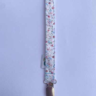 Prendedor de chucha em tecido branco com flores e clip metálico