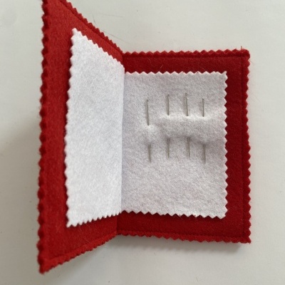 Estojo de feltro vermelho com agulhas de costura dentro
