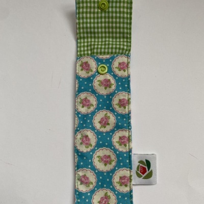 Estojo de tecido azul com flores cor-de-rosa e interior xadrez verde e branco