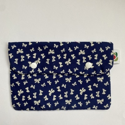 Carteira azul com padrão de laços brancos e fecho de botão