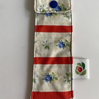 Estojo em tecido com riscas vermelhas e flores azuis com botão azul