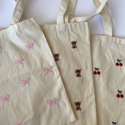 Sacos de lona creme bordados com lacinho rosa, ursinho castanho e cerejas vermelhas