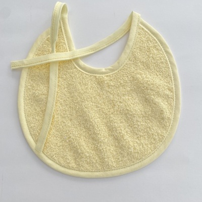 Babete redondo de tecido amarelo claro com fitas para atar
