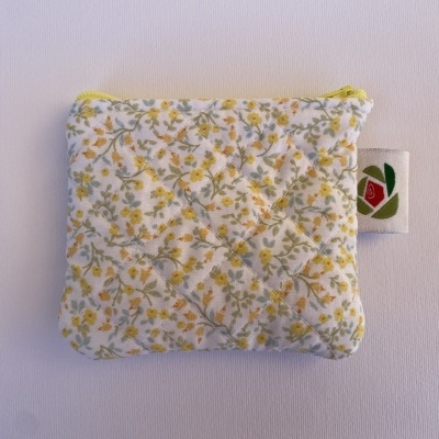 Carteira pequena em tecido matelassado floral com fecho amarelo e etiqueta com rosa