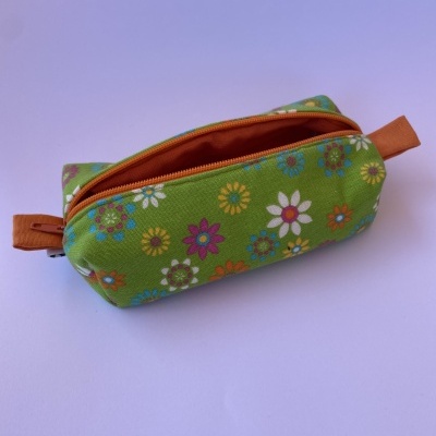 Estojo floral verde com fecho de correr aberto e pegas castanhas.