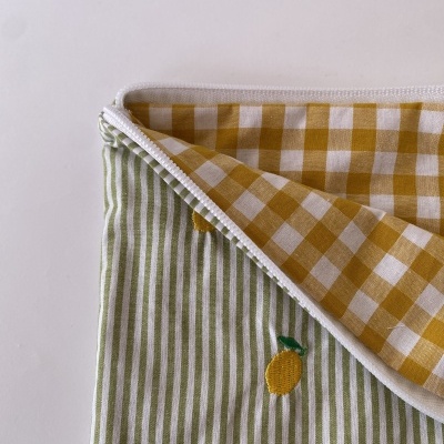 Toalha de tecido com padrão interior em xadrez amarelo e branco e exterior com riscas verdes e brancas com bordados de limões.