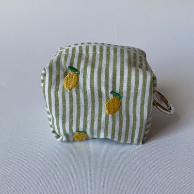 Chaveiro de tecido listrado verde e branco com bordados de limões amarelos e argolas metálicas.