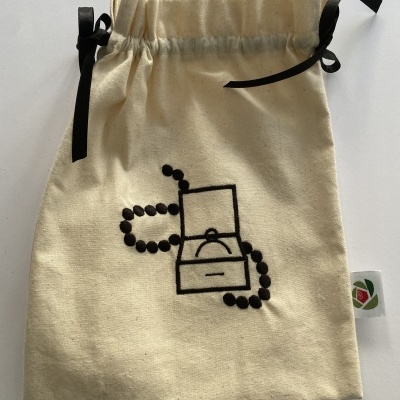 Saco de tecido cru com cordões pretos, bordado de caixa com anel e colar de pérolas