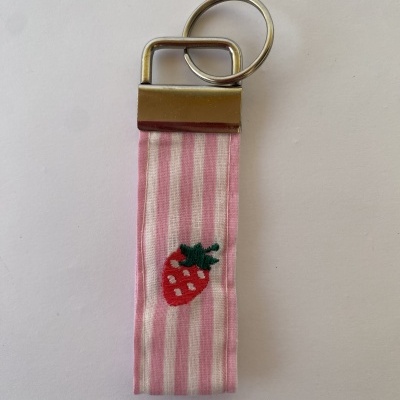 Porta-chaves com tira de tecido rosa às riscas e morango bordado