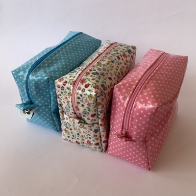 Três necessaires coloridas e estampadas em fundo branco.