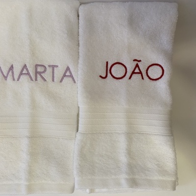 Duas toalhas de banheira brancas personalizadas com nomes bordados em roxo e vermelho