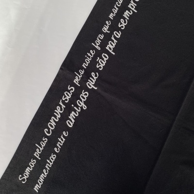 Tecido preto com frase bordada a branco em português