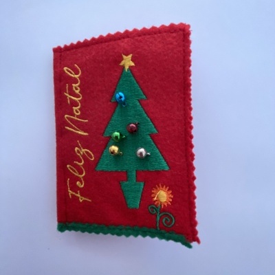 Capa de feltro vermelha com árvore de Natal bordada e texto 'Feliz Natal'