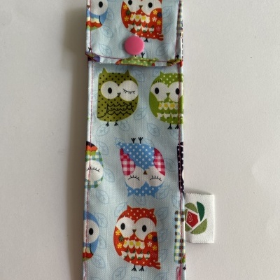 Estojo tecido azul com padrão de corujas coloridas e botão rosa