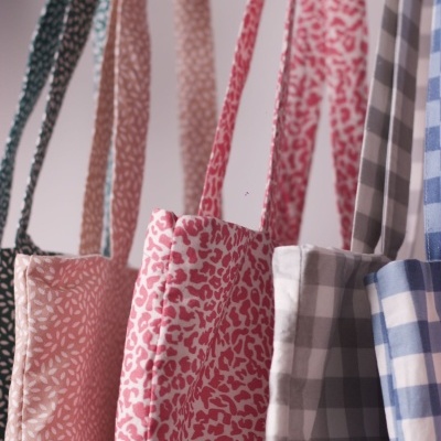 Cinco sacos de tecido pendurados com padrões florais e xadrez em diferentes cores