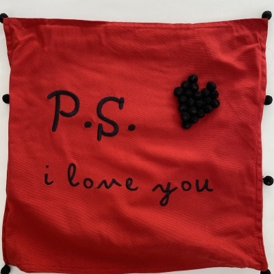Almofada vermelha com texto bordado e coração de pompons pretos