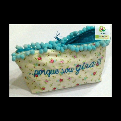 Necessaire floral com frase bordada e fecho azul com pompons