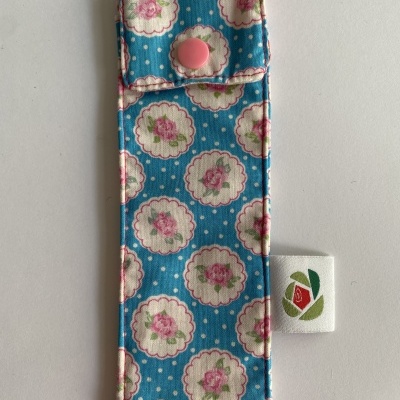 Estojo de tecido azul com padrão floral e botão rosa