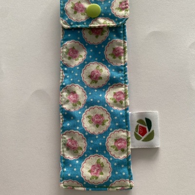 Estojo de tecido azul com padrão floral e fecho em botão verde