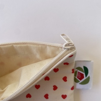Bolsa de tecido com padrão de corações vermelhos e fecho zip branco