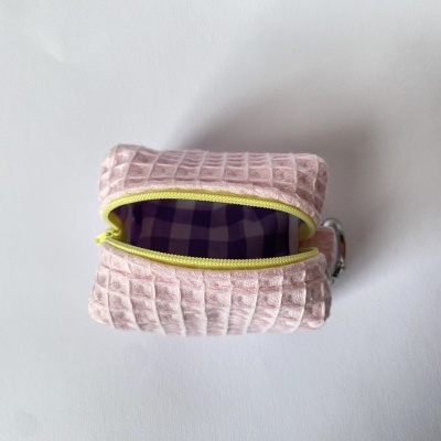 Bolsa pequena rosa com padrão texturizado e fecho amarelo, interior xadrez roxo