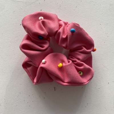 Elástico de cabelo rosa com alfinetes coloridos em fundo branco