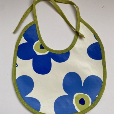 Babete de bebé com flores azuis e verdes e bordas verdes