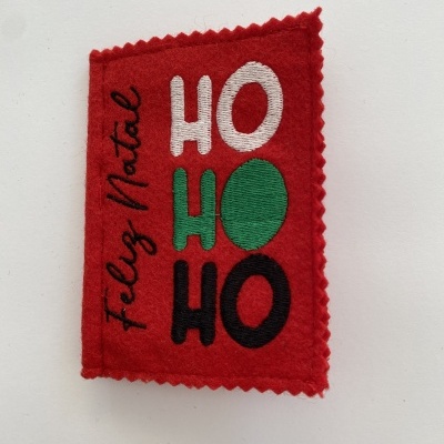 Etiqueta de feltro vermelho com bordado colorido HO HO HO e Feliz Natal