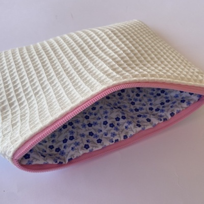 Bolsa retangular branca de tecido com fecho rosa e interior floral azul