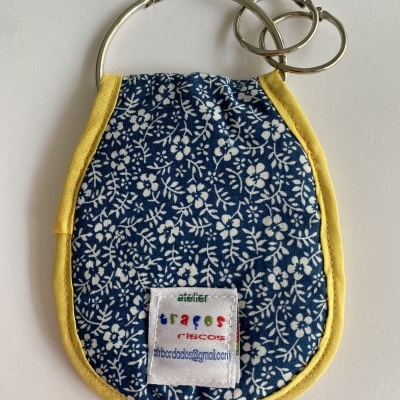 Porta-chaves em tecido azul floral com bordas amarelas e etiqueta com texto colorido