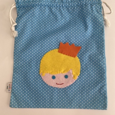 Saco azul com bolinhas brancas e rosto de criança com coroa em feltro