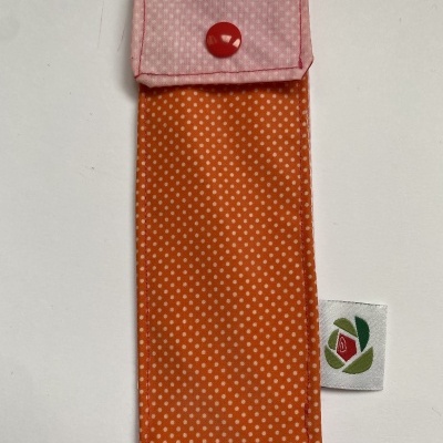 Estojo fino em tecido laranja e rosa com padrão de pontos e botão vermelho