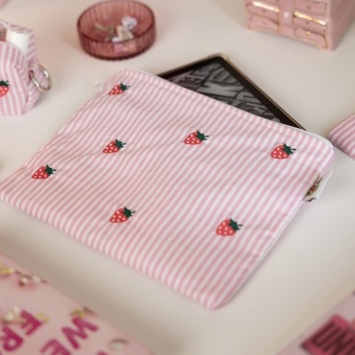 Bolsa rosa listrada com morangos bordados e tablet dentro