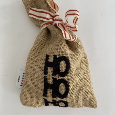 Saco de juta com cordão listrado vermelho e branco e texto preto