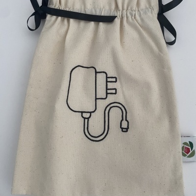 Saco de pano bege com cordão preto e desenho de carregador elétrico