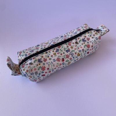 Estojo retangular branco com padrão floral colorido e fecho de correr preto