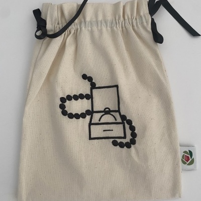 Saco de algodão cru com estampado preto de colar e caixa e cordões para fechar.