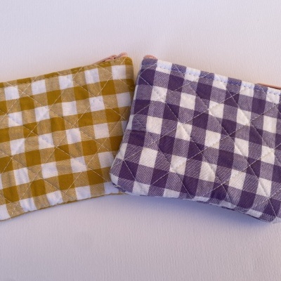 Dois porta-moedas quadriculados, amarelo e branco e roxo e branco, com costura cruzada