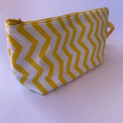 Necessaire branca com padrão de ziguezagues amarelos e fecho de correr amarelo