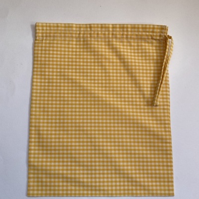Saco de tecido amarelo e branco com padrão de quadrados pequenos e fecho de cordão.
