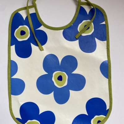 babete para bebé com padrão de flores azuis e verdes sobre fundo branco