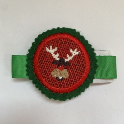 Prendedor de fita verde com decoração de rena bordada em tecido vermelho