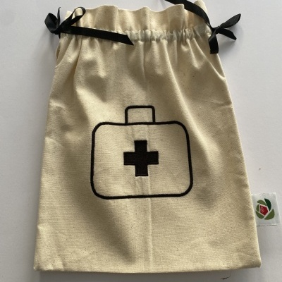 Saco de tecido cru com cordões pretos e desenho de mala de primeiros socorros com cruz preta.