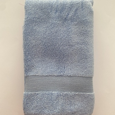 Toalha azul clara de algodão dobrada com faixa decorativa