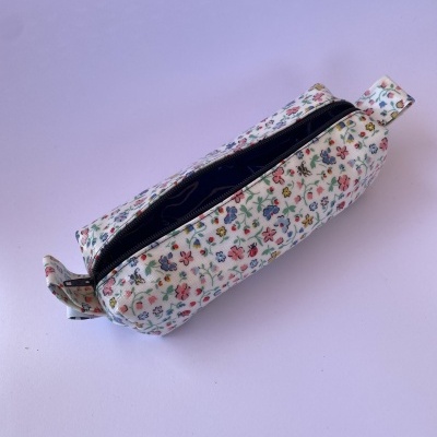 Estojo retangular branco com padrão floral colorido e fecho de correr preto
