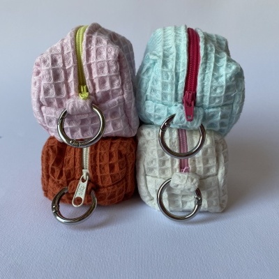 Quatro pequenas bolsas coloridas com padrão waffle, fechos coloridos e argolas metálicas