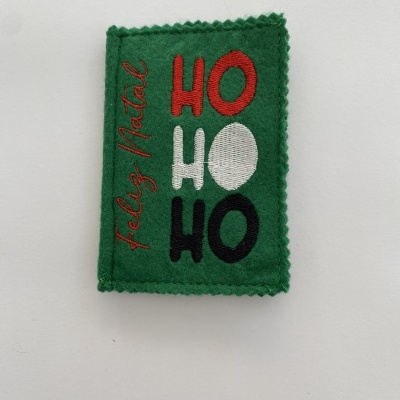 Patch bordado verde com texto de Natal colorido em fundo branco.